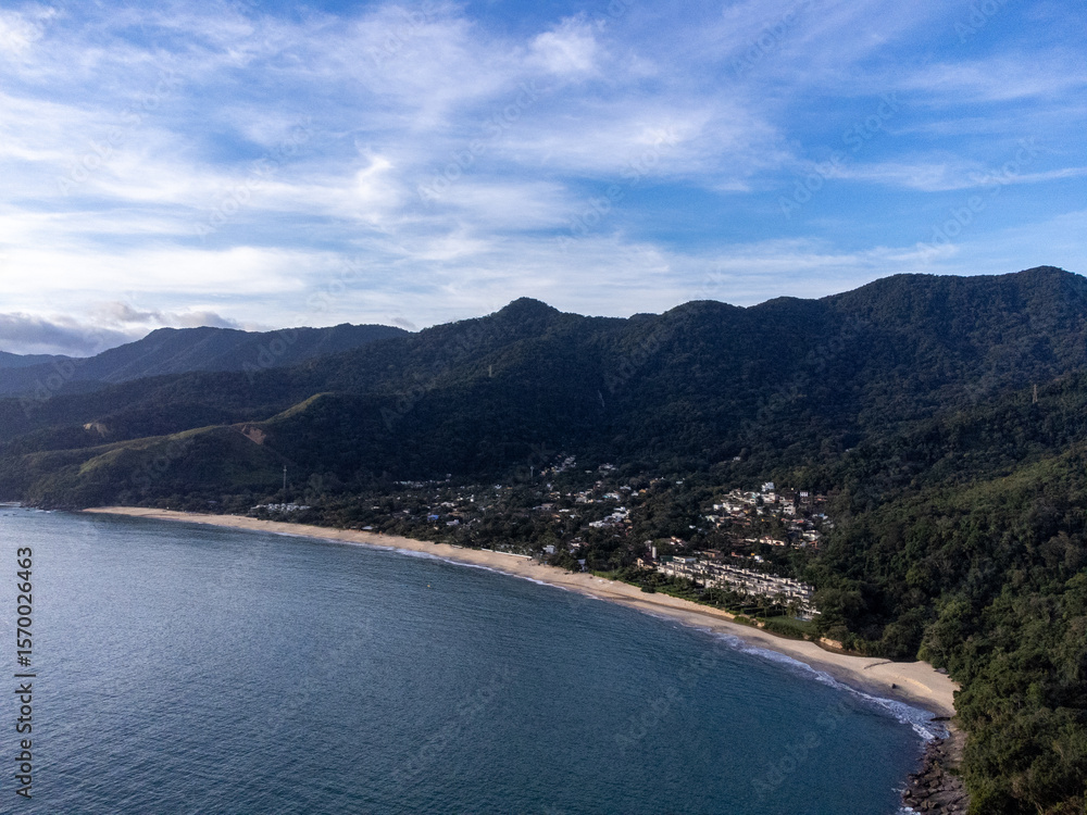 Setting sun on beautiful tropical beach amidst forested mountains Setting sun on beautiful tropical beach amidst forested mountains