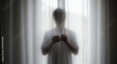 A person silhouetted behind sheer curtains, creating a mysterious and introspective atmosphere. 