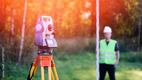 Surveyor engineer topographer with leveling rail on background of forest and tool for geodetic work. Total station and topographer cadastral engineer when performing cadastral work for land surveying.