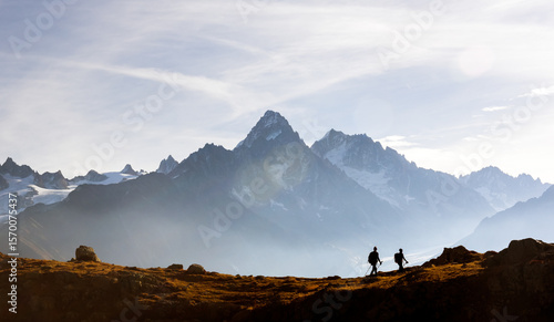 Two hikers walking above Lac de Cheserys in the French Alps near Chamonix. Scenic Monte Bianco range mountain view with Mont Blanc peaks and alpine adventure vibe