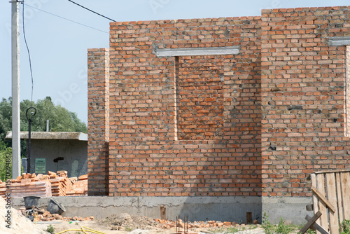 Obraz na plátně Workers are constructing a brick house with exposed walls and window openings