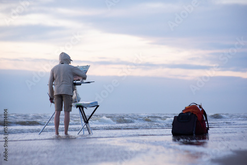 A man on the beach painting the sea 