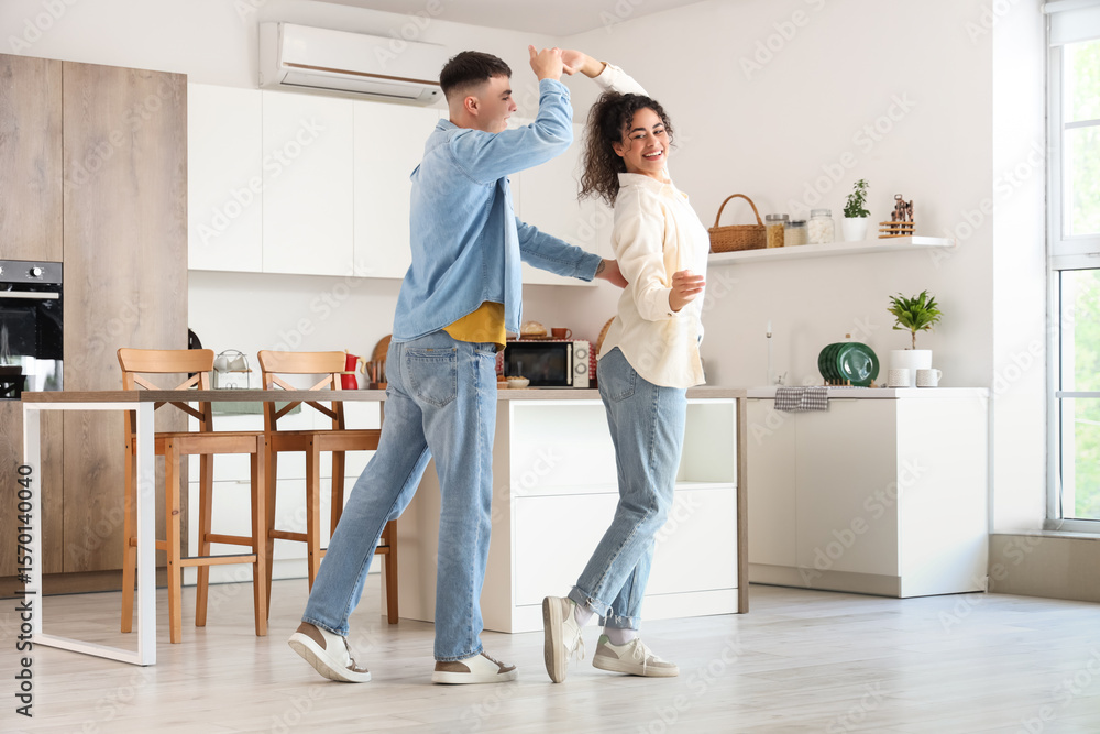 Obraz premium Happy young beautiful couple dancing in kitchen at home