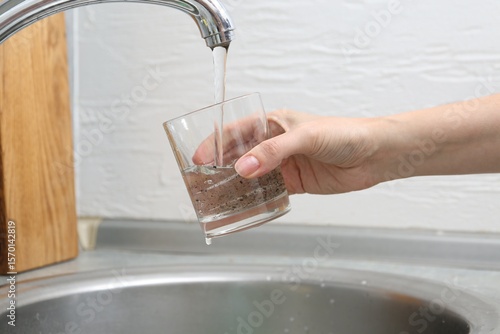 Obraz na płótnie Woman filling glass with dirty tap water indoors, closeup