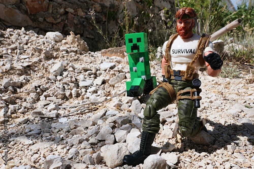 Naklejka premium GI JOE action figure of survival instructor Outback, Classified edition 2023, chased by green explosive LEGO Minecraft Creeper mob on sunlit rocks in Croatian garden.