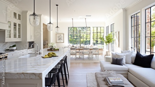 Bright, open concept kitchen-living area featuring white cabinetry, marble island and windows