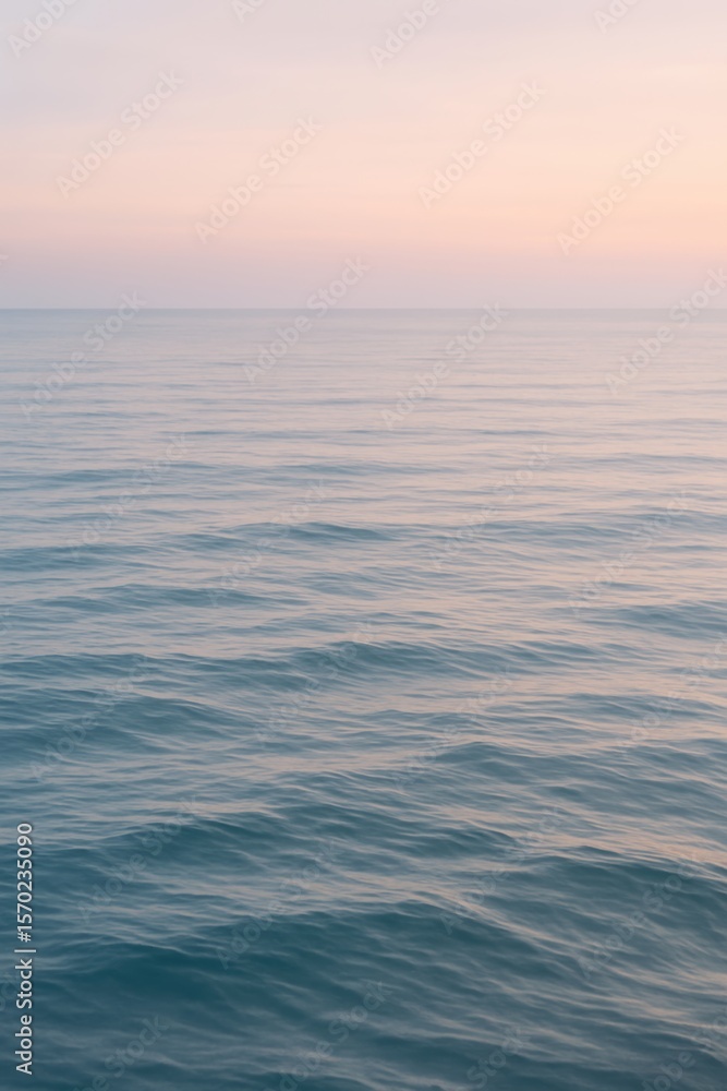 Fototapeta premium Tranquil ocean at sunset with gentle waves and pink sky
