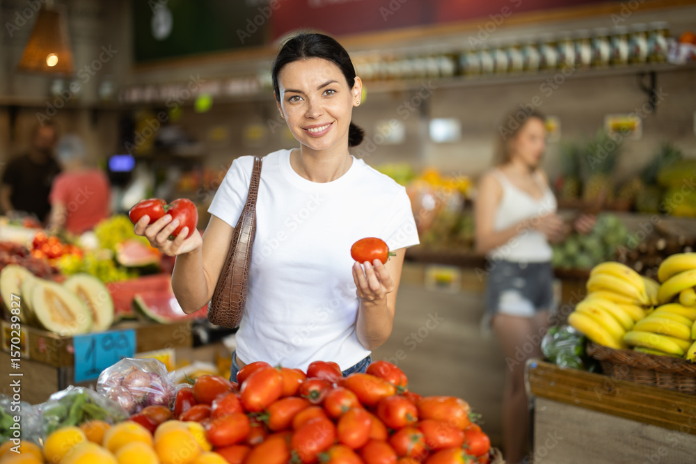 Adult woman buyer choosing fresh tomatoes in vegetable shop Adult woman buyer choosing fresh tomatoes in vegetable shop