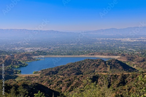 The Hollywood Hills fade into the San Fernando Valley with the San Gabriel Mountains and Santa Susana Mountains in the background and the Encino Reservoir in the foreground