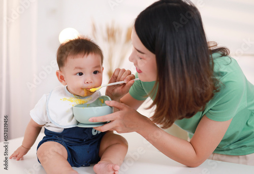 Bild auf Leinwand The mother who is feeding her little boy on the table wants to be happy