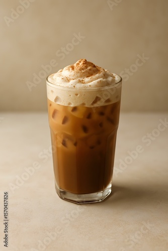 Refreshing Iced Coffee Beverage with Creamy Foam Topping and Cinnamon Dusting, Served in a Clear Glass on Light Background