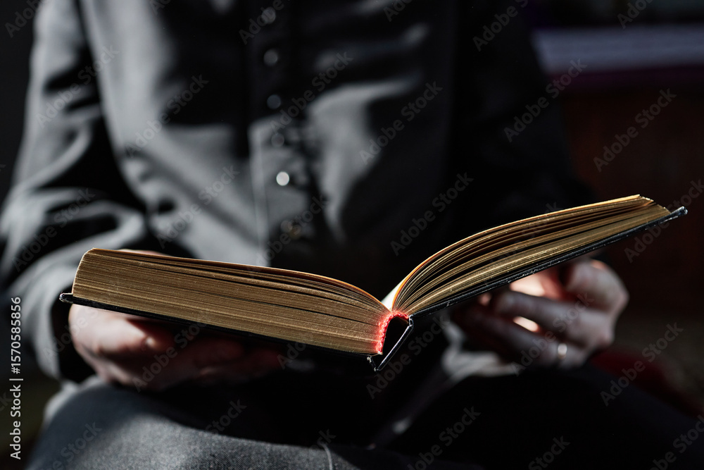 Εκτύπωση καμβά Man sitting in church holding open book with both hands, reading attentively, we