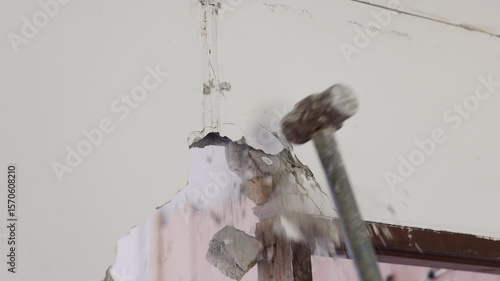 Worker is Removing a concrete wall in a house.