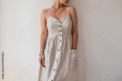Chic female in trendy dress with buttons, complemented by an exquisite necklace, showcasing modern elegance and style