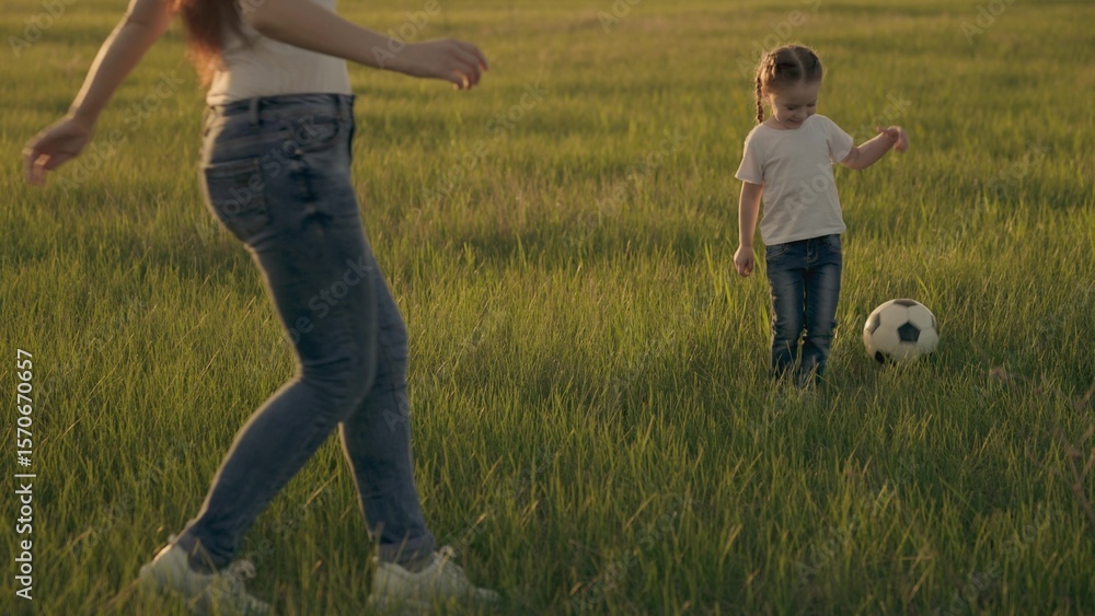Little child runs across the green football field playing football at sunset in the sky, kid kicks the ball and catches up with him, the concept of a happy childhood life, active healthy baby. Little child runs across the green football field playing football at sunset in the sky, kid kicks the ball and catches up with him, the concept of a happy childhood life, active healthy baby.