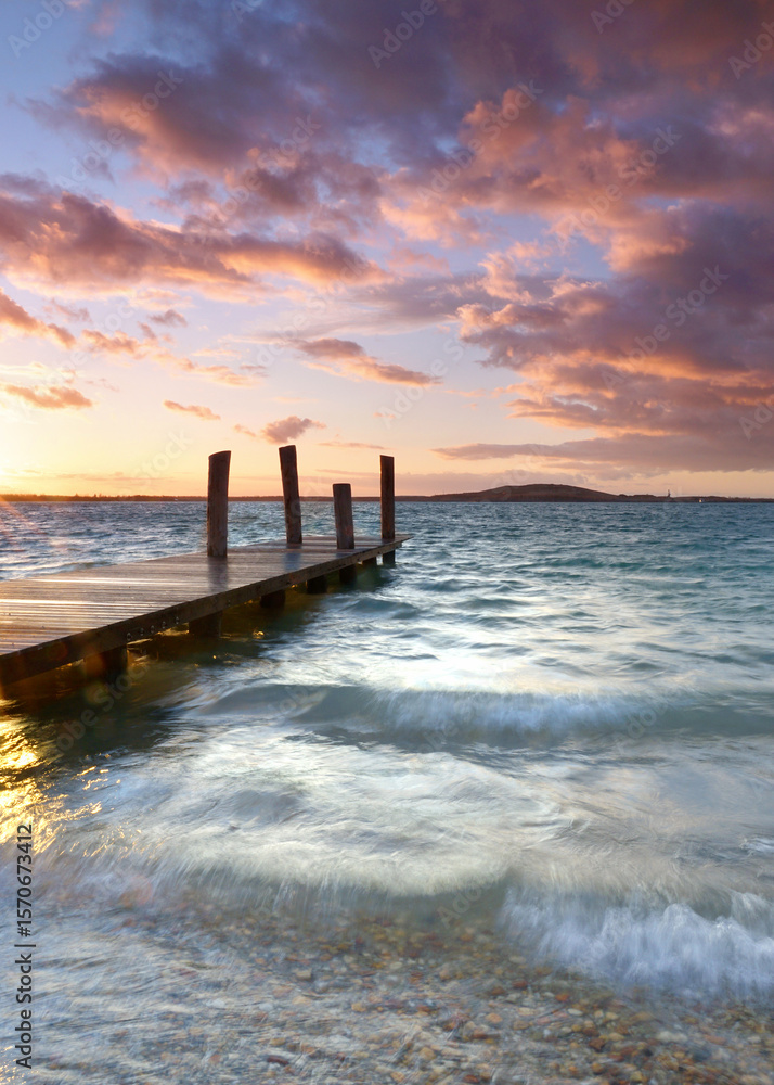 Obraz premium Serene Sunset Reflections: Wooden Pier over Tranquil Waters
