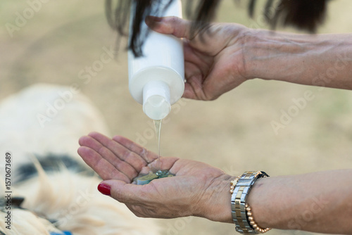 Woman pouring shampoo on hand, preparing to wash a dog