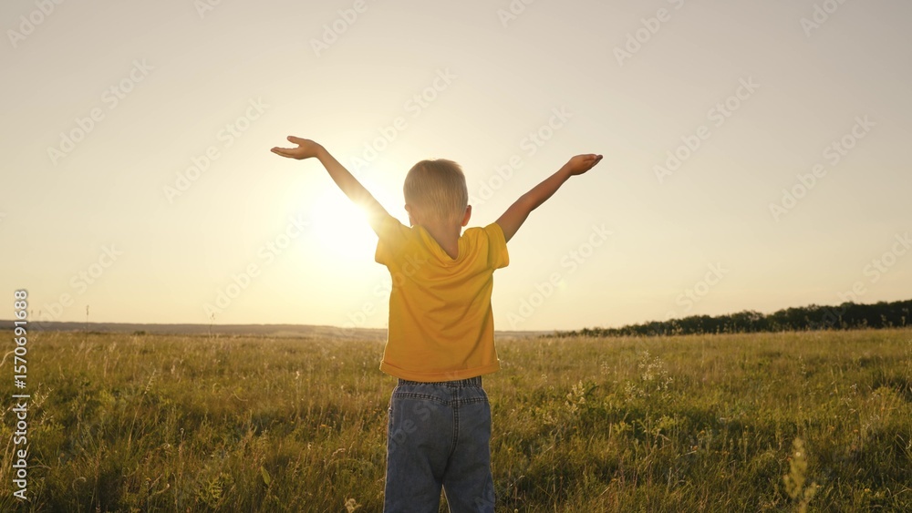 little child with hands raised up at sunset, boy believes in religion in the rays sunlight in the sky, happy family, kid son looks into the distance dawn, boy's summer sunny day, adventure travel fun. little child with hands raised up at sunset, boy believes in religion in the rays sunlight in the sky, happy family, kid son looks into the distance dawn, boy's summer sunny day, adventure travel fun.