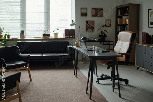 Canvastavla Empty modern therapy office showing desk with laptop and glass of water, armchai