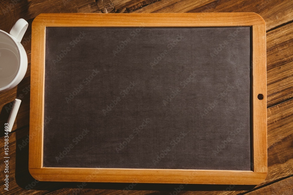 Obraz premium Flat design showing wood-framed chalkboard is lying on plank tabletop, with ceramic mug and chalk