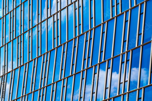 Wallpaper Mural Reflective blue glass building facade with vertical window strips and cloud reflections Torontodigital.ca