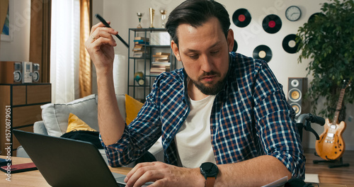 Photography A man sits at his home desk surrounded by documents