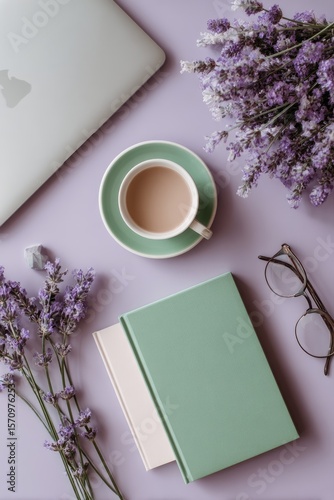 Flatlay of a laptop, coffee, book, lavender, and glasses on a purple surface.  Muted pastel tones and a calming aesthetic