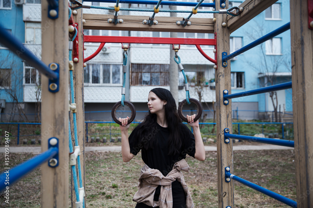 Fototapeta premium A sad teenage girl sits on a playground on a spring evening. 