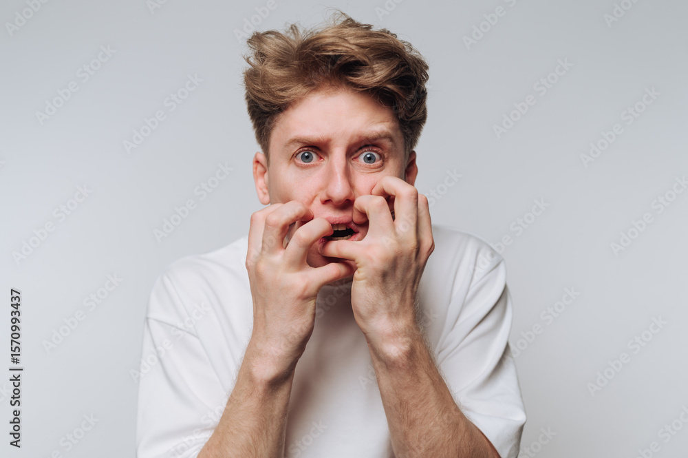 Young man expresses fear and anxiety in a neutral setting during a personal moment of distress Young man expresses fear and anxiety in a neutral setting during a personal moment of distress