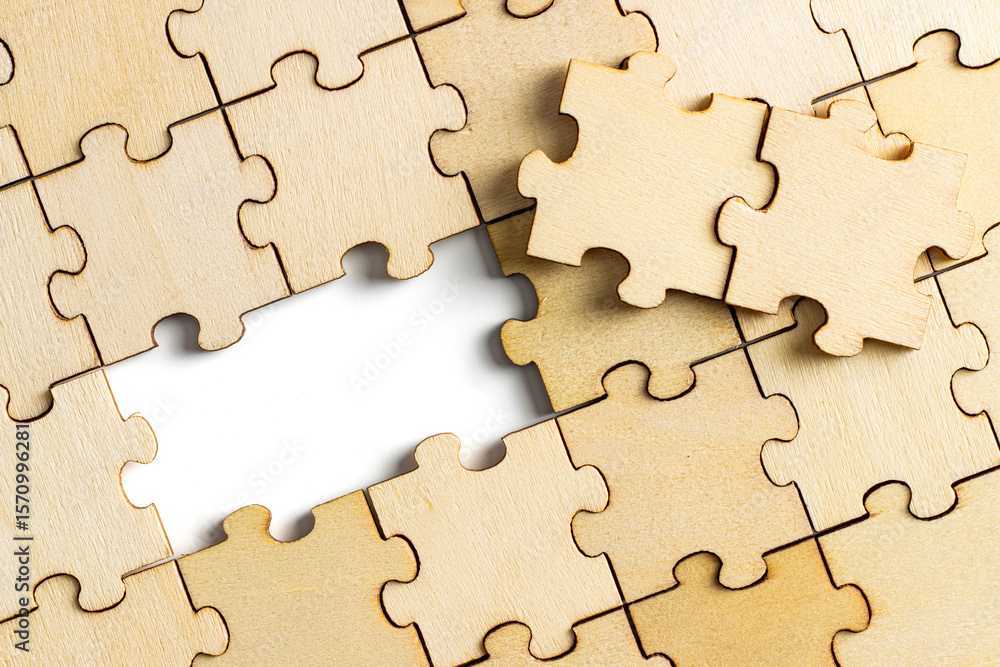Fototapeta premium wooden jigsaw puzzle with missing pieces exposing empty white background for copy space.