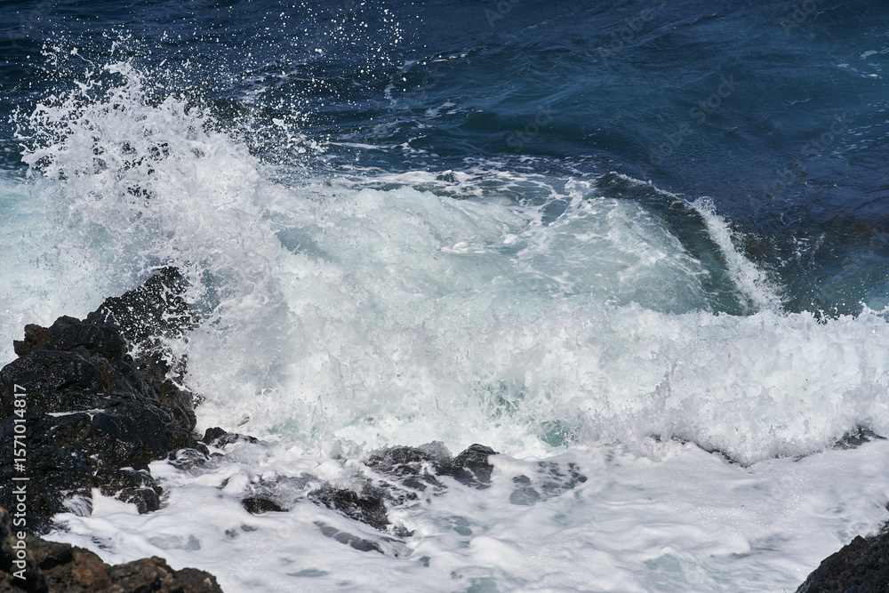 Fototapeta premium Waves hitting volcanic shoreline