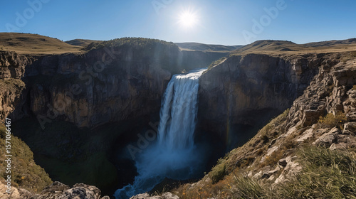 Majestic waterfall cascading into a deep canyon under a bright sunny sky capturing natural beauty and scenic landscape photography