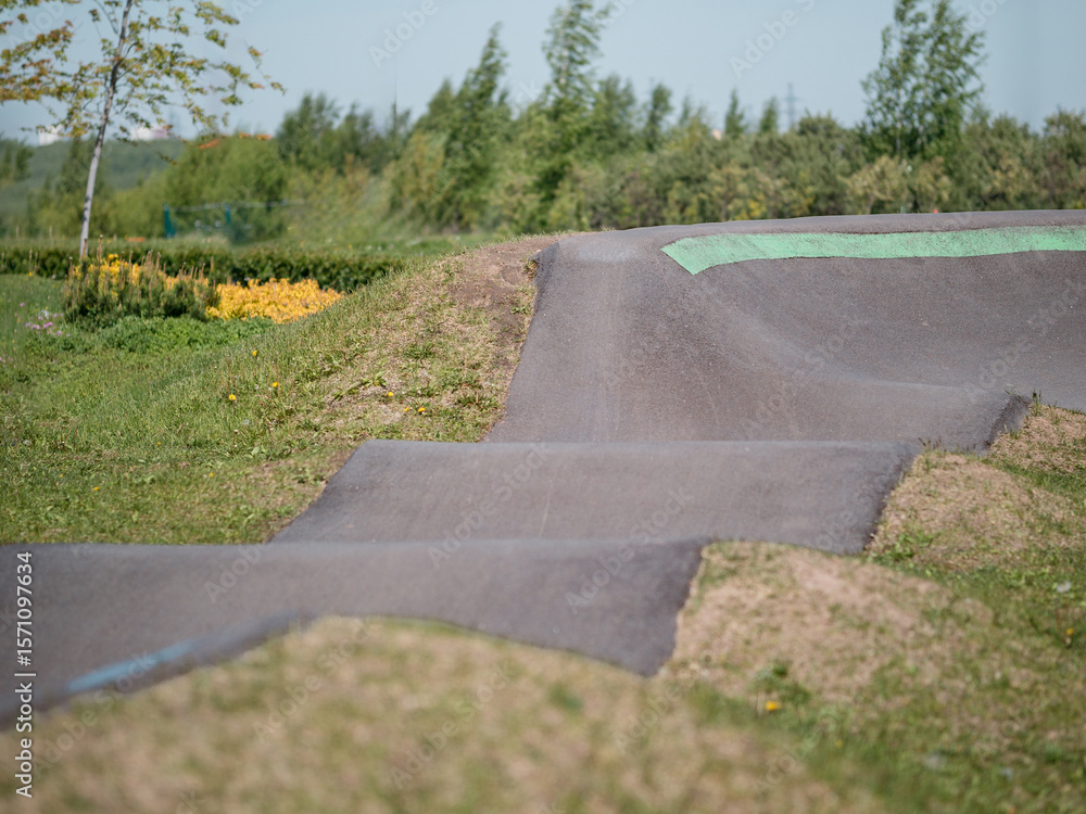 Fototapeta premium Pump track close up. Pumptrack curves with lines. Asphalted bicycle race track, pump track outdoors, kids playground. Racing speed track