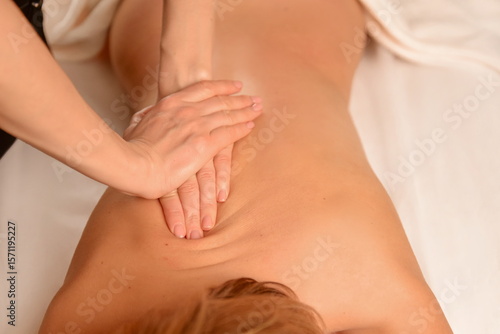 Massage therapy session Hands-on treatment for back pain relief slender Caucasian woman. Massage, health, wellness.