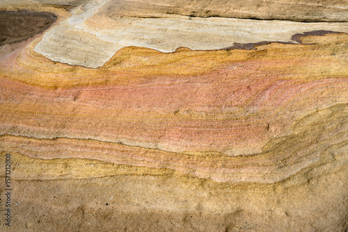 Detail shot of layered pink, yellow and orange sedimentary rock