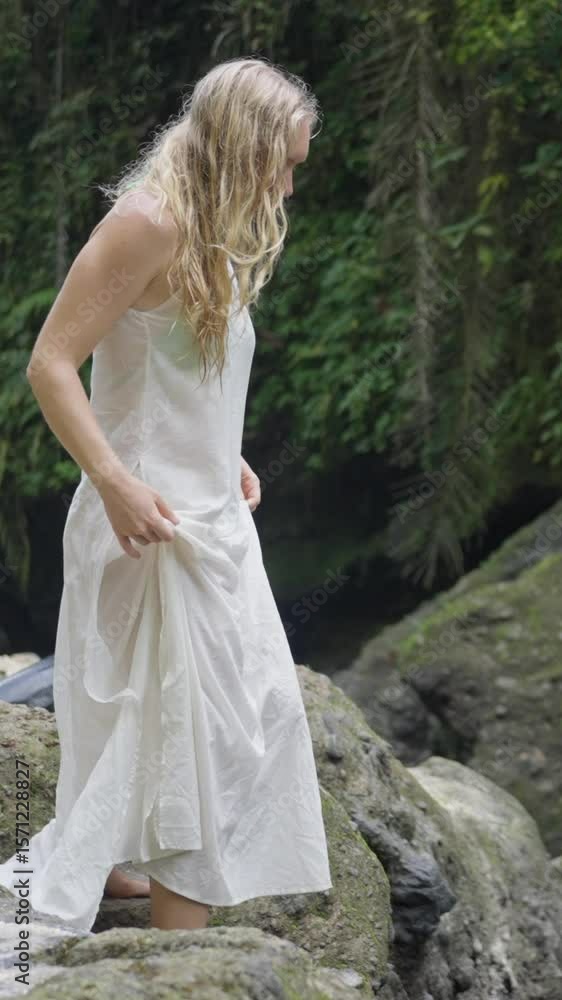 A model in a flowing white dress stands elegantly by a scenic waterside, embodying beauty A model in a flowing white dress stands elegantly by a scenic waterside, embodying beauty