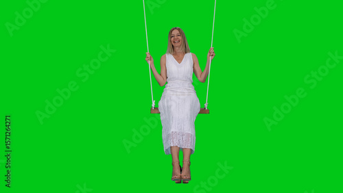 Canvas-taulu Beautiful smiling adult woman in long white dress swinging on the rope see-saw o