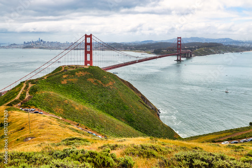 Wallpaper Mural Panoramic view of the Golden Gate Bridge spanning San Francisco Bay with cityscape, lush hills, and boats, captured from a high vantage point on a cloudy spring day Torontodigital.ca