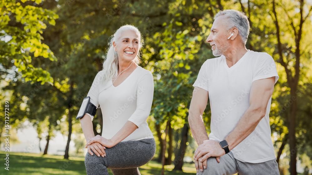 Fototapeta premium Fitness, stretching and senior couple in park for healthy body, wellness and active workout outdoors. Retirement, sports and man and woman stretch legs on grass for exercise, training and warm up