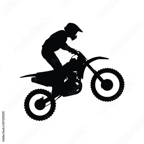 Silhouette of a motocross rider performing a wheelie on a dirt bike