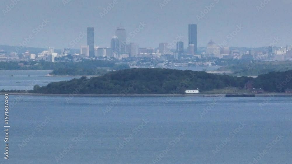 Boston city skyline in distance looking over Boston Harbor with boats and homes on shoreline in Massachusetts Boston city skyline in distance looking over Boston Harbor with boats and homes on shoreline in Massachusetts