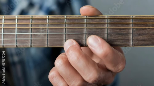 Hand playing acoustic guitar fretboard