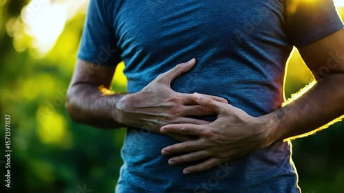 Man clutching stomach experiencing abdominal pain outdoors