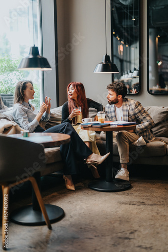 Konstfotografi Three friends engage in a lively conversation while enjoying drinks in a cozy cafe