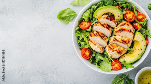 Grilled chicken breast salad with avocado, tomatoes, arugula and fresh greens on minimalist backdrop, promoting healthy eating habits