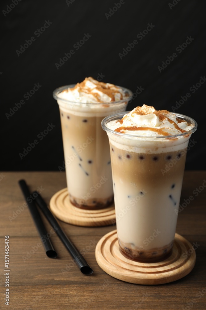Tasty milk bubble tea in plastic cups on wooden table Tasty milk bubble tea in plastic cups on wooden table