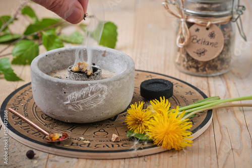 Placing incense on a glowing coal - holy smoke ritual on Beltane