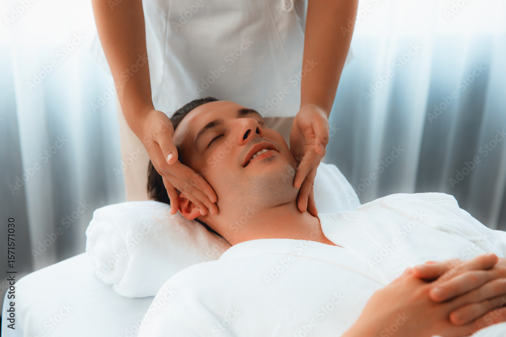 Caucasian man enjoying relaxing anti-stress head massage and pampering facial beauty skin recreation leisure in dayspa modern light ambient at luxury resort or hotel spa salon. Quiescent Caucasian man enjoying relaxing anti-stress head massage and pampering facial beauty skin recreation leisure in dayspa modern light ambient at luxury resort or hotel spa salon. Quiescent