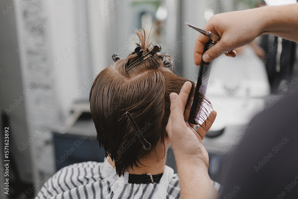 Fototapeta premium Male haircutting session in barbershop hair salon with hairstylist using scissors and comb