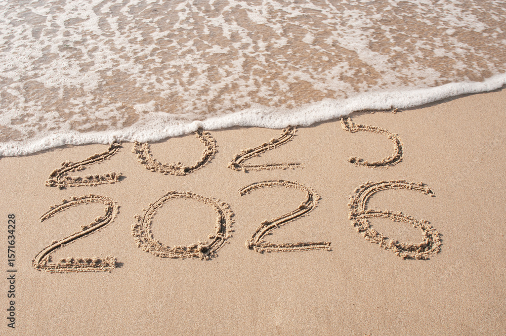 Fototapeta premium Inscription 2025 and 2026 numbers written on sand. New Year 2025 replace 2026. Concept on the sea beach